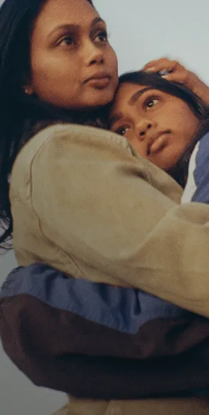 妈妈和女儿抱在一起，妈妈手里拿着手机